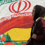 A woman walks past a mural of Iran’s national flag on Thursday in central Tehran. (Stringer/AFP via Getty Images)