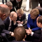 Russian President Vladimir Putin (center-left) huddles with Germany Chancellor Angela Merkel (center-right) during Sunday’s Berlin summit on Libya. (Alexei NikolskyTASS via Getty Images)