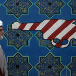 An Iranian cleric walks past a mural on the wall of the former US Embassy, February 2007, Tehran, Iran. (Majid Saeedi/Getty Images)